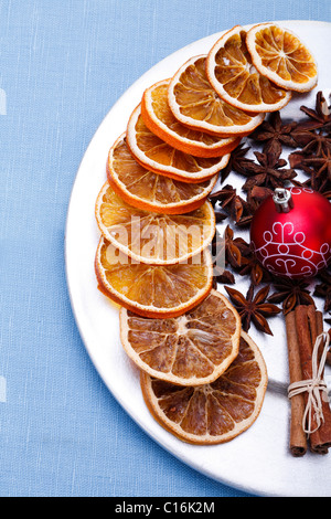 Tranches d'orange séchée, l'anis étoilé, Boule de Noël et des bâtons de cannelle dans une assiette Banque D'Images