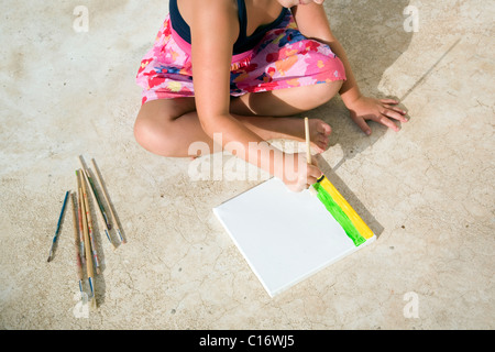 Girl painting on canvas assis sur le plancher Banque D'Images