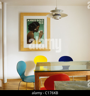 Papillon de couleur vive des chaises autour d'une table à manger en verre surmontée avec Ludwig Hohlwein 'Marco Polo' poster en t Banque D'Images