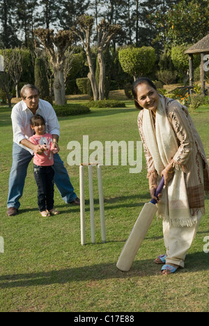 Famille à jouer au cricket in lawn Banque D'Images
