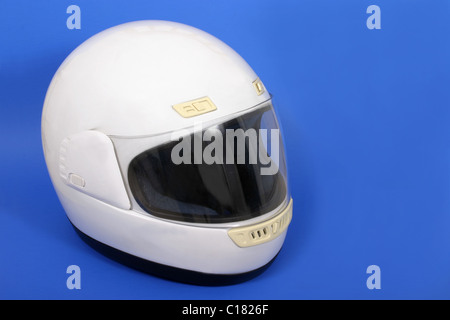 Casque de moto intégral blanc sur fond bleu. Banque D'Images