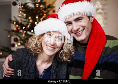 Couple avec Santa hats in front of tree Banque D'Images