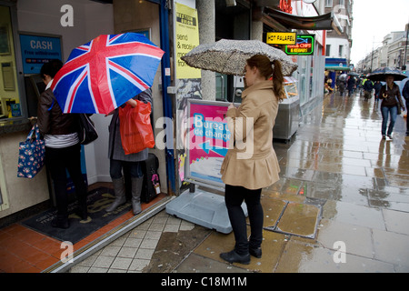 La mise en queue sur jour de pluie à utiliser une caisse automatique à Londres Banque D'Images