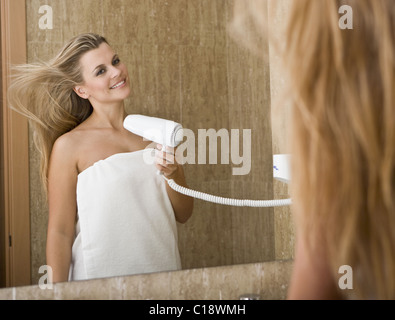 Belle jeune femme à l'aide d'un sèche-cheveux Banque D'Images