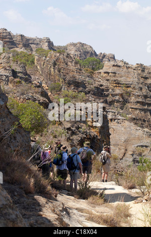 Les touristes ayant une pause tandis que les randonnées de Parc National d'Isalo, Madagascar, avec un fond de falaises de grès jurassique. Banque D'Images