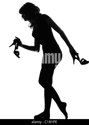 Silhouette dans l'ombre d'une jeune femme marche tout nu sur la pointe des pieds maintenant hautes chaussures de talon en studio sur fond blanc Banque D'Images