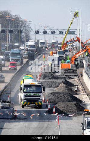 Occupé génie civil élargissement de la route chantier de construction Cherry picker prêt à mélanger béton ciment camions et camions autoroute M25 Essex Angleterre Royaume-Uni Banque D'Images