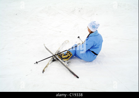 La jeune fille de sportswear sur ski de montagne a diminué et se situe sur la neige, la ville de Domodedovo, dans la région de Moscou, Russie Banque D'Images