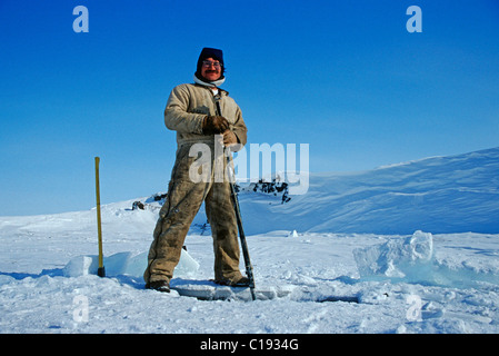 Pêche inuit dans un trou dans la glace de la rivière Colville, Nuiqsut, sur la côte de l'océan Arctique dans l'extrême nord de l'Alaska Banque D'Images