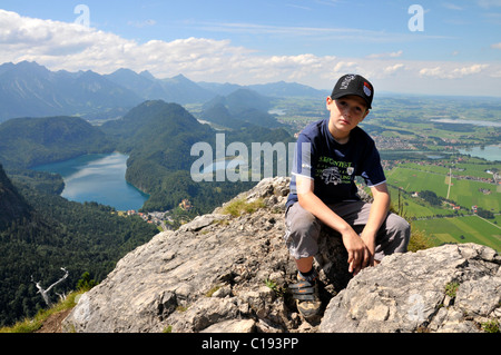 Un garçon de 8 ans prendre du repos, sur la montagne Tegelberg, derrière le lac Forggensee, Alpes Allgaeu, Bavaria, Germany, Europe Banque D'Images