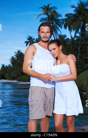 Romantic couple standing next to palm tree Banque D'Images