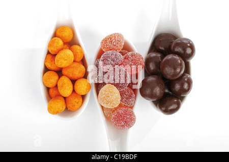 Arachides rôties avec une croûte croustillante, noisettes enrobées de chocolat enrobés de sucre et de la gomme en gouttes cuillères en céramique Banque D'Images