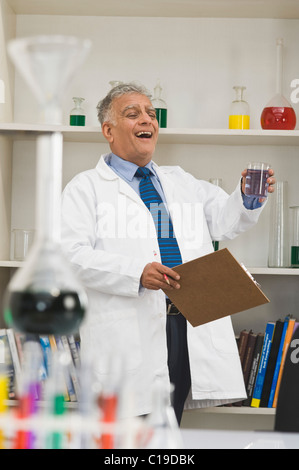 Scientist doing expérience scientifique dans un laboratoire et souriant Banque D'Images