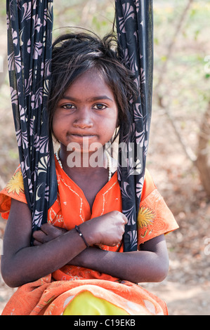 Heureux jeunes pauvres caste inférieure Indian street girl smiling assis dans un sari swing. L'Andhra Pradesh, Inde Banque D'Images