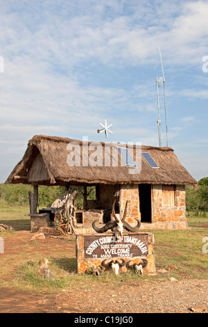 Panneaux solaires et éolienne sur toit de chaume game reserve, à l'entrée de bureau le Masai Mara au Kenya Banque D'Images