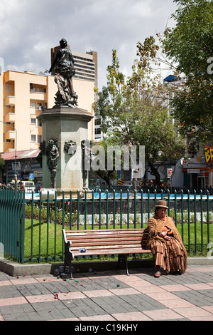 Femme portant des vêtements typiques assis sur banc dans Avanida 16 de Julio, La Paz, Bolivie, Amérique du Sud. Banque D'Images