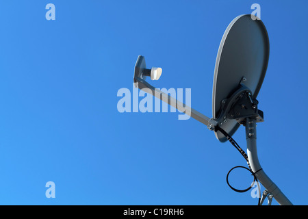 Une antenne satellite HD modernes monté sur un poteau de métal gris, pointant vers un ciel bleu clair. Banque D'Images