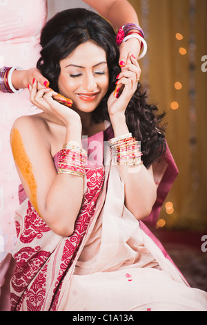 Les amis et la famille de la mariée s'appliquer la pâte de curcuma à son corps comme une partie de Gaye Holud de cérémonie Mariage Bengali Banque D'Images