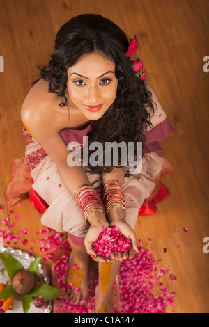 Portrait d'une mariée en robe traditionnelle Bengali holding rose petals Banque D'Images