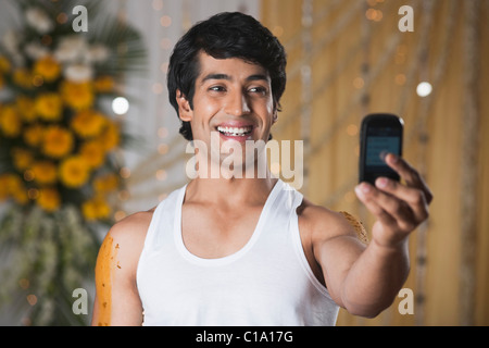 L'homme de prendre une photo de lui-même avec un téléphone mobile et souriant Banque D'Images