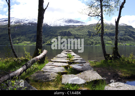 Jetée de pierre Jølstravatnet, comté de Sogn og Fjordane, en Norvège, avec lac et montagnes en arrière-plan Banque D'Images