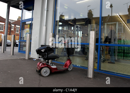 Les personnes âgées à l'extérieur d'un scooter mobile supermarché de Littlehampton, West Sussex, UK. Banque D'Images