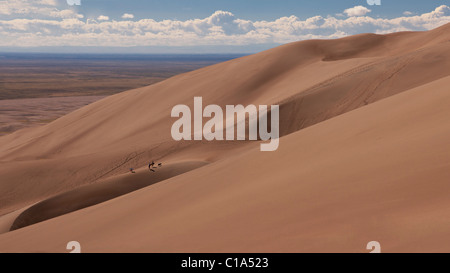3 personnes et de chien portant jusqu'dune grande dune de sable rouge à l'échelle ajouter attraction pittoresque Great Sand Dunes National Monument, Colorado, USA ouest Banque D'Images