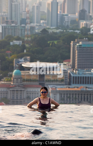 Woman swimming in pool à Marina Bay Sands SkyPark avec ville en arrière-plan. Marina Bay, Singapour Banque D'Images