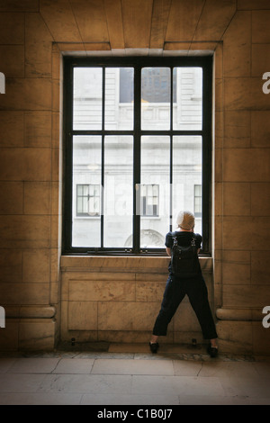 Girl with hat à la recherche d'une grande fenêtre Banque D'Images