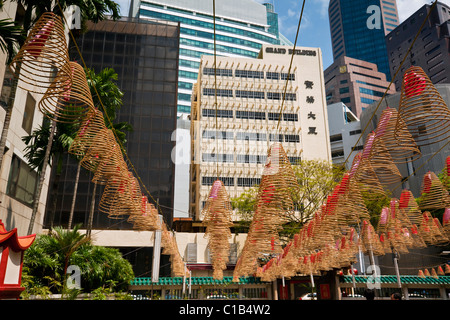 Bobines d'encens en spirale avec ville en arrière-plan à Wak Hai Cheng Bio Temple, Raffles Place, Singapour Banque D'Images