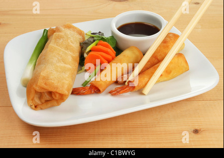 Rouleaux de crêpes chinoises,filo, de la salade et les crevettes enveloppées de baguettes sur une plaque Banque D'Images