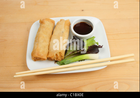 Rouleaux de crêpes chinoises, salade et baguettes sur une plaque Banque D'Images