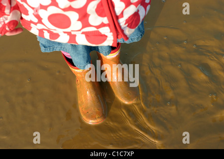 Jeune fille debout dans des flaques boueuses Banque D'Images