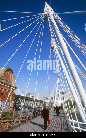 Les banlieusards de marcher à travers Hungerford Bridge sur la Tamise vers Charing Cross, Londres Banque D'Images