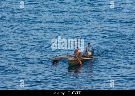 Madagascar, de l'Océan Indien, au large de la côte de l'île de Nosy Be. Les hommes malgaches en pirogue en bois. Banque D'Images