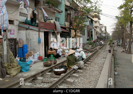 Des gens assis et de travailler sur la voie ferrée de la ligne de chemin de fer principale dans Hanoi Vietnam Banque D'Images