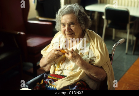 Sourire d'un patient âgé d'arthrite rhumatoïde dans ses mains de manger une orange à l'hôpital salle sociale Pays de Galles 1980 KATHY DEWITT Banque D'Images