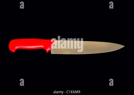 Grand couteau de cuisine avec poignée rouge isolé sur black with clipping path Banque D'Images