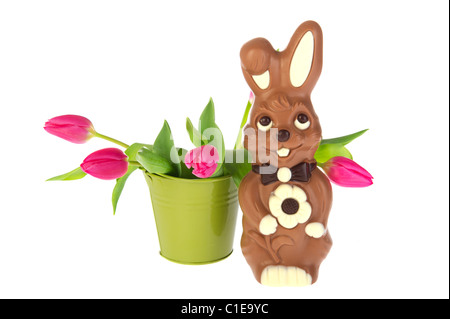 Lièvre de pâques en chocolat avec une benne de tulipes roses au printemps Banque D'Images