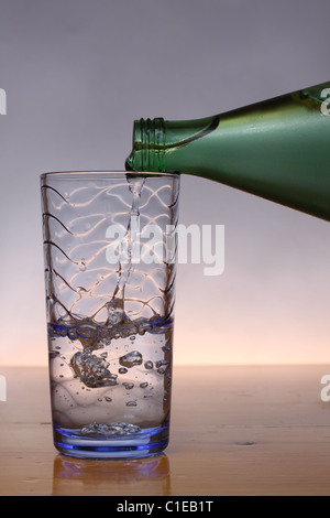 Verser l'eau froide à partir de la bouteille verte en verre bleu Banque D'Images