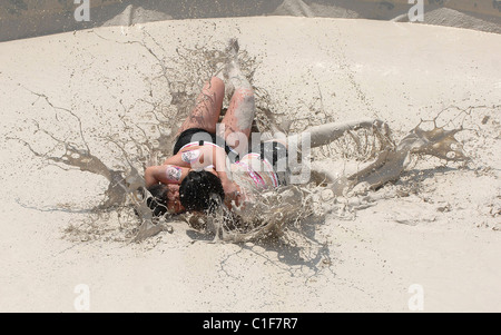 Championnats du monde Mud-Wrestling deux femelles sales dans une fosse de la pince pendant une journée internationale de la femme en cas de boue-lutte Banque D'Images