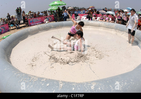 Championnats du monde Mud-Wrestling deux femelles sales dans une fosse de la pince pendant une journée internationale de la femme en cas de boue-lutte Banque D'Images