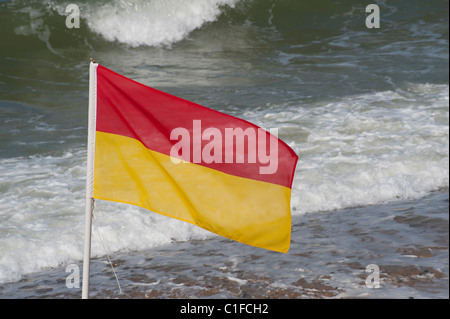 Drapeau rouge et jaune sur une plage anglaise indiquant cette plage est surveillée par des maîtres nageurs sauveteurs Banque D'Images