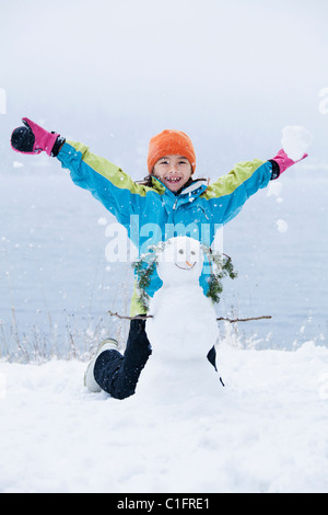 Mixed Race girl building snowman Banque D'Images