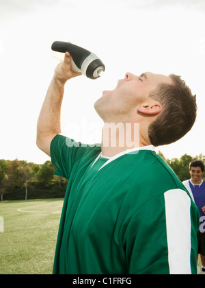 Le joueur de soccer du Caucase l'eau potable sur le terrain de soccer Banque D'Images