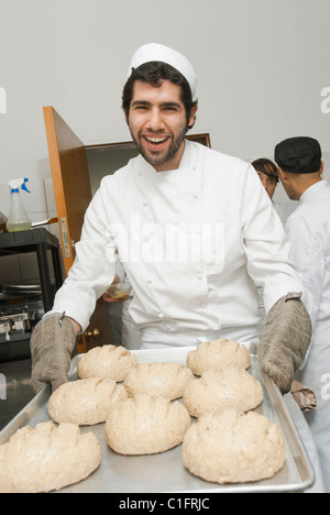 Baker carrying tray de pâte à pain en cuisine boulangerie Banque D'Images