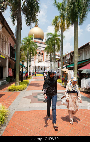 Les femmes malais à marcher le long de la rue Bussorah avec la Mosquée Sultan en arrière-plan. Quartier arabe, Singapour Banque D'Images
