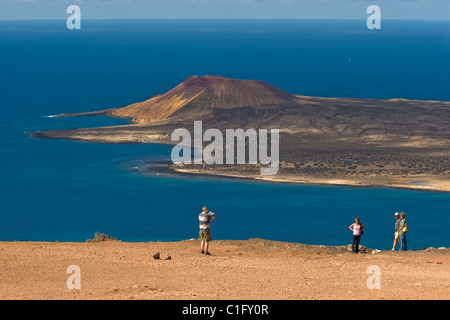 Les touristes au Mirador Del Rio Lookout sur la côte nord-ouest de Lanzarote, avec un cône volcanique sur l'île de Graciosa, au-delà des îles Canaries Banque D'Images