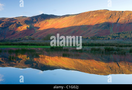 Rochers de haute montagne dans la lumière du soleil du matin, qui se reflète dans l'eau, Derwent Parc National de Lake District, Cumbria, Angleterre. Banque D'Images