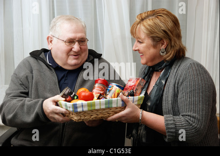 Homme âgé gagnant un prix de tirage et présenté avec une boîte de goodies Banque D'Images